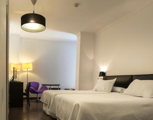 a bedroom with a large bed and a purple chair at Catedral Almería in Almería