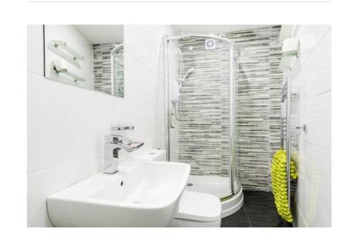 uma casa de banho branca com um lavatório e um chuveiro em treetops flat3 Hall Green B28 em Birmingham