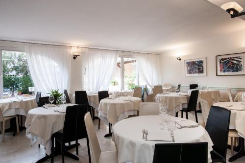 un comedor con mesas blancas y sillas negras en Hotel Sabrina, en Castiglione della Pescaia