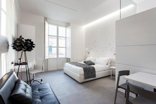 a white bedroom with a bed and a couch at Nostos rooms & Apartments in Syracuse