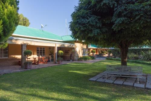 a park bench under a tree next to a building at GaMamadi Guest Farm in Nelspoort