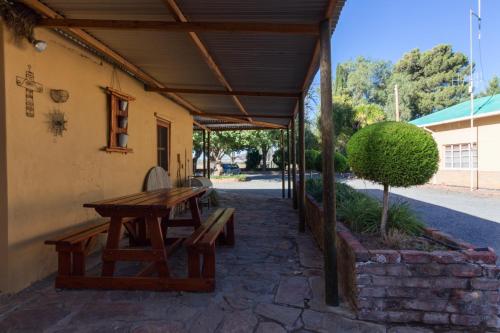 a patio with a wooden table and a bench at GaMamadi Guest Farm in Nelspoort