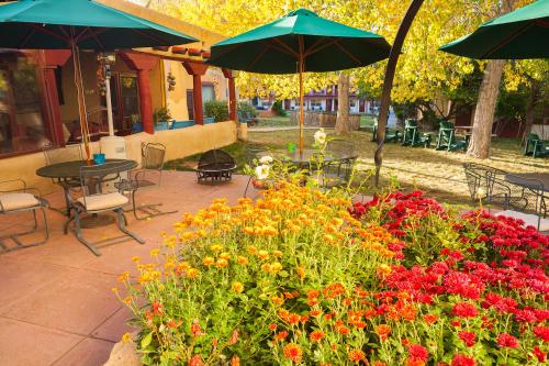 a patio with a bunch of flowers and tables and umbrellas at El Pueblo Lodge in Taos