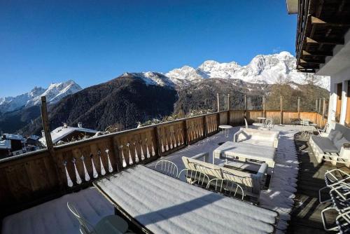 a balcony with tables and chairs and snow covered mountains at HG Hotel La Caminatha in Val di Zoldo