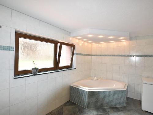 uma casa de banho branca com uma banheira e uma janela em Modern Apartment in Kropelin near the Sea em Kröpelin