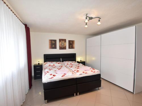 a bedroom with a bed with red flowers on it at Modern Apartment in Kropelin near the Sea in Kröpelin