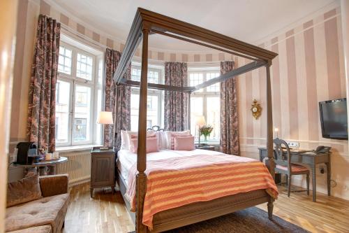 a bedroom with a canopy bed and a television at Hotel Kung Carl, WorldHotels Crafted in Stockholm