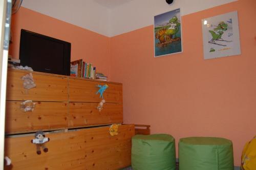 a bedroom with a dresser with a tv and green chairs at Haus Lechner Apartments in Sankt Jakob in Haus