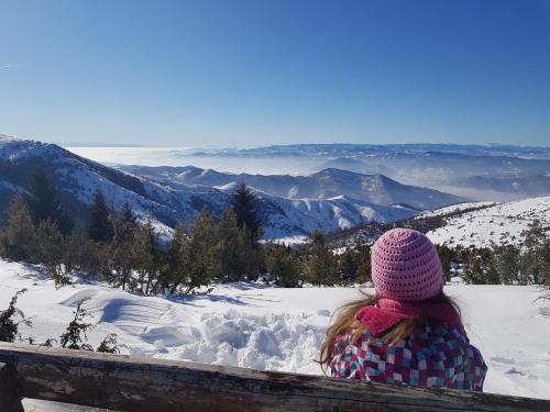 コパオニクにあるApartmani Kraljevi Čardaciの雪の中のベンチに座る少女