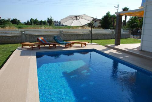 a swimming pool with two benches and an umbrella at Villa Arance in Fethiye