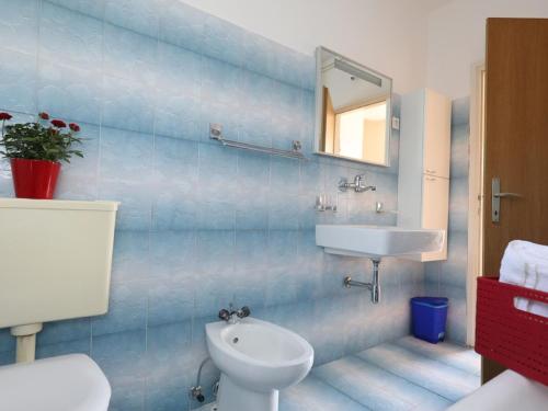 a blue tiled bathroom with a sink and a toilet at Pleasant Apartment in Zidarici near the Sea in Malinska