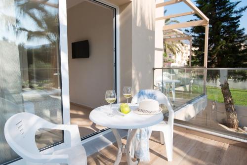 a white table with two chairs and wine glasses on a balcony at Blue Sky Apartments in Malia