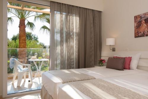 a bedroom with a bed and a balcony with a palm tree at Blue Sky Apartments in Malia