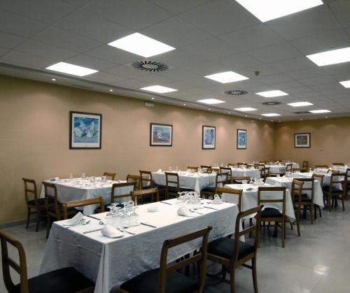 a dining room with tables and chairs with white table cloth at Hotel Chané in Puebla de Alfindén