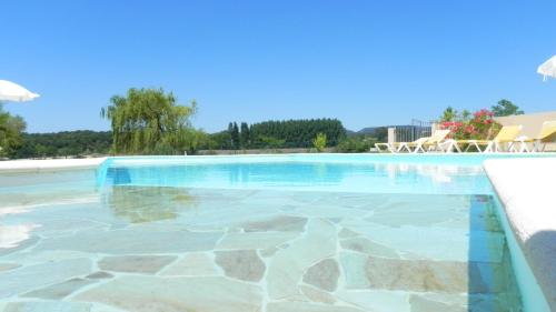 a swimming pool with clear blue water at Hôtel La Bastide d'Iris in Vagnas