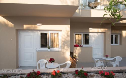 a patio with white chairs and a table and a table at Blue Sky Apartments in Malia