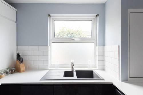 a white kitchen with a sink and a window at The Nine Elms Residence in London