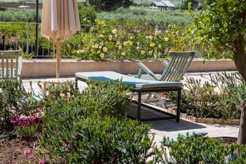 a patio with two chairs and an umbrella and some bushes at Resort Fontes Episcopi in Aragona