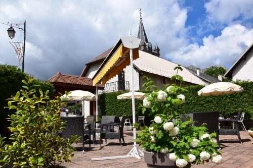 a building with chairs and umbrellas and a church at Hotel le Chalet in Gresse-en-Vercors