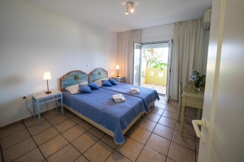 um quarto com uma cama azul e um edredão azul em Iason Hotel Apartments em Giosonas