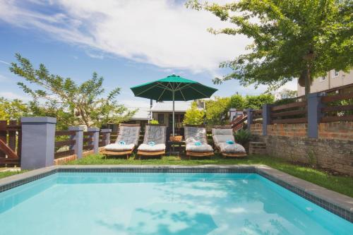 a swimming pool with chairs and an umbrella at A Hilltop Country Retreat in Swellendam