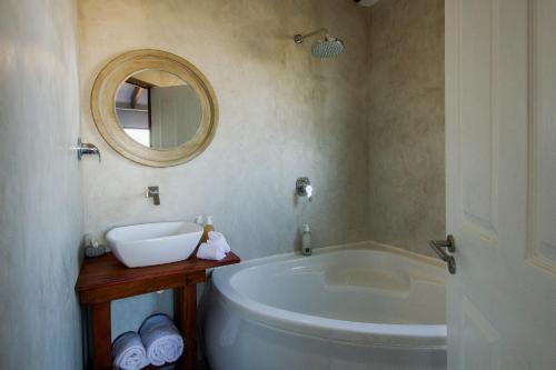 a bathroom with a tub and a sink and a mirror at A Hilltop Country Retreat in Swellendam