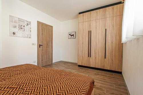 1 dormitorio con 1 cama y armario de madera en The Fox Apartment, en Vrchlabí