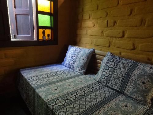 a bed with pillows and a window in a room at Chalé Chapada dos Veadeiros in Cavalcante