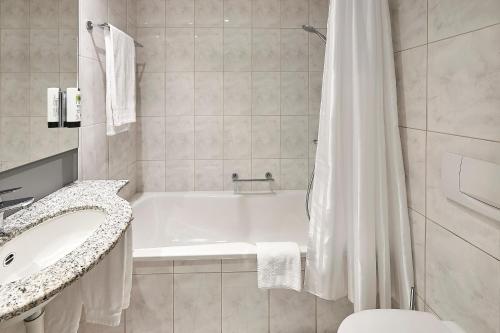 a white bathroom with a tub and a sink at Hotel Central Luzern in Luzern