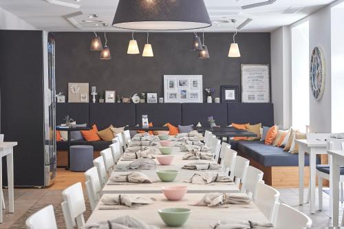 une longue table avec des tables et des chaises blanches dans un restaurant dans l'établissement Hotel Central Luzern, à Lucerne