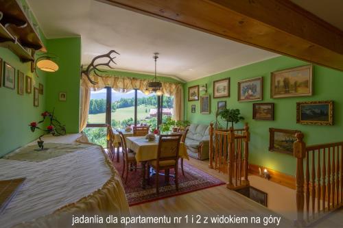 Habitación con mesa y comedor con paredes verdes. en Willa Gwiazda, en Szklarska Poręba