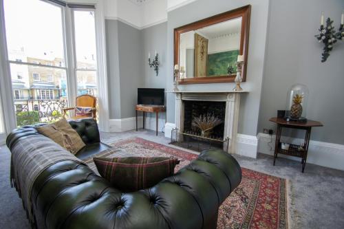 a living room with a leather couch and a fireplace at Regency Apartment - Sea View - by Brighton Holiday Lets in Brighton & Hove