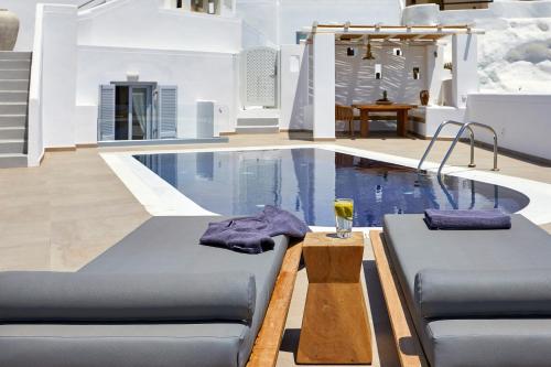 a pool with two beds and a drink on a table at Volcano View by Caldera Collection in Fira