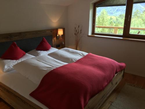 Schlafzimmer mit einem Bett mit roten Kissen und einem Fenster in der Unterkunft Haus Dietrich in Serfaus