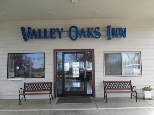 dois bancos em frente a uma estalagem de carvalho do vale em Valley Oaks Inn Woodland em Woodland