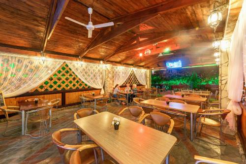 un restaurante con mesas y sillas de madera y techo en Assol, en Gelendzhik
