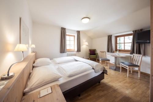 a bedroom with a large bed and a dining room at Hotel Masatsch in Caldaro