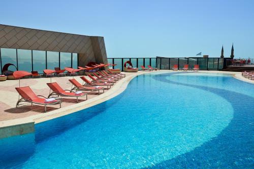 a large swimming pool with lounge chairs on a building at Apartments by Fairmont Baku Flame Towers in Baku