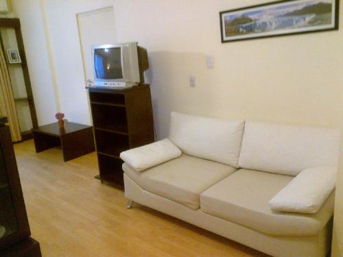 sala de estar con sofá blanco y TV en Córdoba Suites Recoleta en Buenos Aires