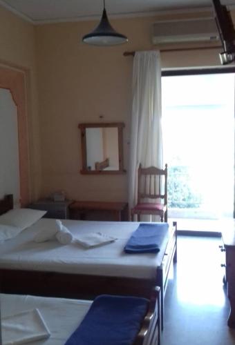 a bedroom with two beds and a chair and a window at Hotel Ionio in Katakolon