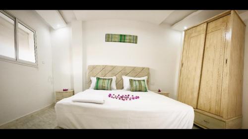 um quarto com uma cama branca com flores cor-de-rosa em Dwiret Hayet Kélibia em Kelibia