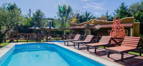 a swimming pool with chairs and a house at Complejo Retana in Potrero de los Funes