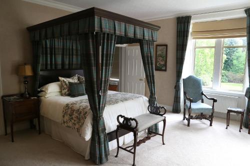 a bedroom with a canopy bed and a chair at Carnach House in Nairn