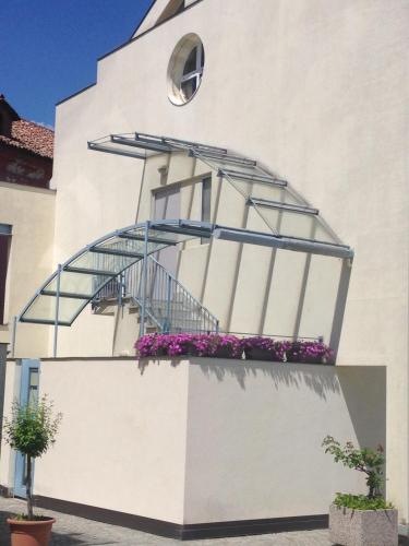 a white building with a balcony with purple flowers at Casa Agnese in Alba