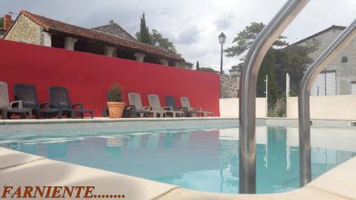 - une piscine avec des chaises à côté d'un mur rouge dans l'établissement Mas de Trescouvieux, à Laval-Saint-Roman