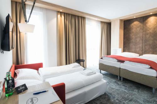 ザンクト・ペルテンにあるDas Alfredのベッド2台とテレビが備わるホテルルームです。