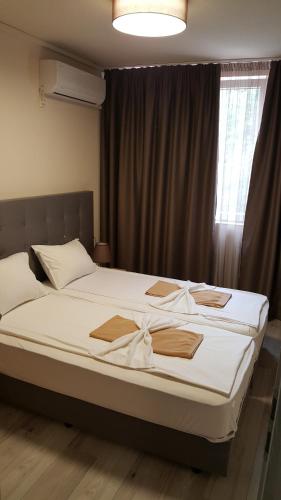 um quarto com uma cama com lençóis brancos e uma janela em Sity Sandanski em Sandanski