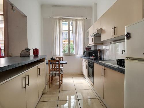 une cuisine avec des armoires blanches et une table et des chaises dans l'établissement Nestor&Jeeves - SQUARE PROMENADE - Central - Direct access sea, à Nice