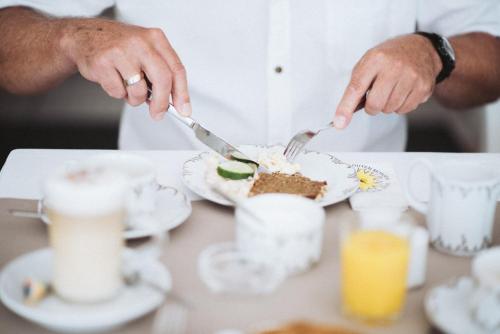 a person cutting a piece of cake on a plate at Waastwinj - 500m vom Strand in Utersum