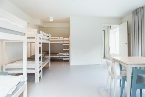 ブルージュにあるSnuffel Youth Hostelの二段ベッド、テーブル、椅子が備わる客室です。